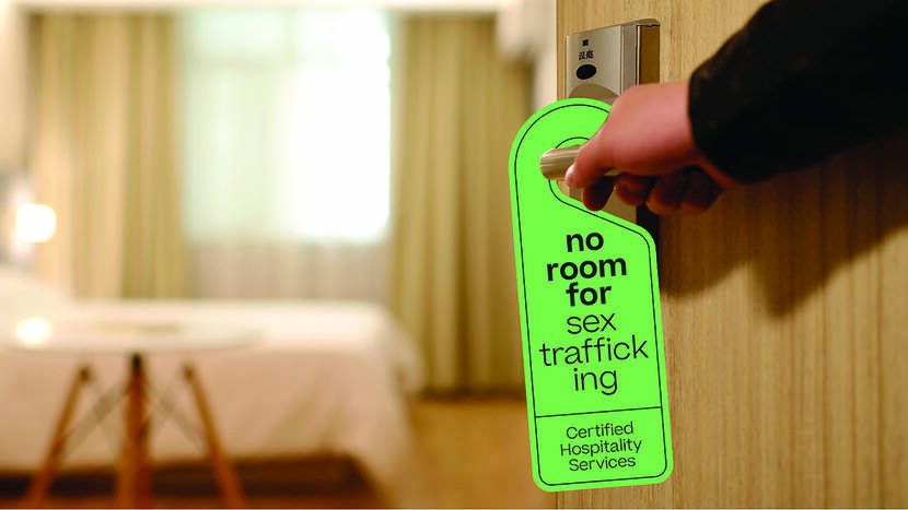 Hotelkamerdeur met deurhanger met de tekst No Room for Sex Trafficking Certified Hospitality Services